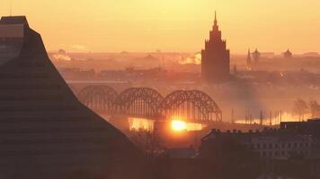 Golden sunrise over Riga, Latvia, with the arched railway bridge spanning the Daugava River and the Latvian Academy of Sciences in morning mist. video