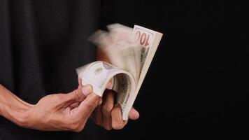 A man is fanning a bunch of money. Man's hand holding cash and show them video