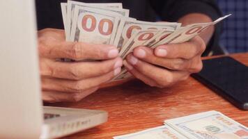 Close up of an employee is counting his bunch of money on his desk. front view video