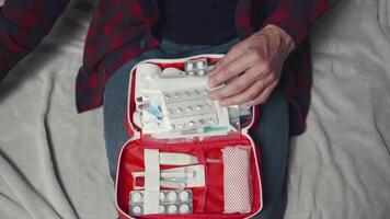 A man is sitting on a bed with a red and white medical kit video