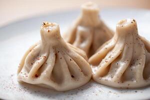 Traditional khinkali dumplings on a plate with pepper seasoning sprinkled on top and soft focus background photo