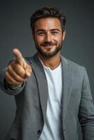 Smiling businessman pointing finger at you on gray background photo