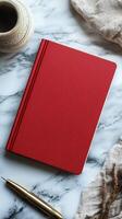 Red notebook with pen and cup on marble table photo
