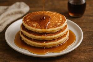 A stack of pancakes with syrup being poured on top photo