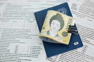 South Korean won money bills in big amount lies on table with passport and tax forms close up photo