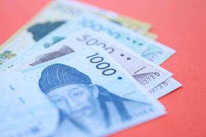 South Korean bills in big amount lies on red color table photo