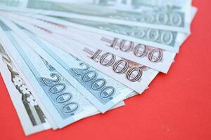 North Korean money bills in big amount lies on red color table close up photo