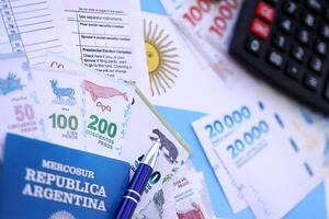 Argentine pesos money in big amount lies on table with pen, calculator, passport and tax forms photo