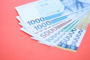 South Korean money in big amount lies on red color table photo