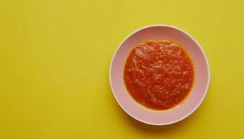 Tomato sauce red cream on bowl yellow background photo