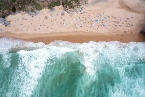 Ocean beach with turquoise waters and tourists relaxing on sandy seashore photo