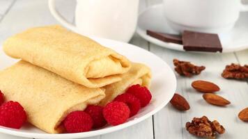 A plate with a roll of pancakes, raspberries and almonds video