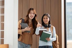 Friendship and Academic Success. Two students posing with their books and devices after a productive session. photo