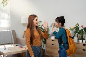 Back to School and High-Fives. A mother and daughter celebrate with a playful high-five before leaving for school. photo
