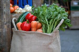 Fresh vegetables in a burlap sack displayed at a local market in the afternoon sunlight photo