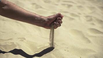 An extreme close-up of a man's clenched fist releasing dry sand through fingers as wind scatters it - a striking slow motion metaphor for land desertification video