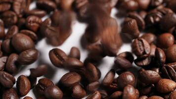 A close-up shot of coffee beans in motion, creating a dynamic and textured view. The rich brown tones of the beans stand out against a subtle, blurred background. video