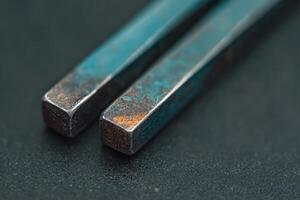 Rusty metal tools resting on a dark surface in a workshop setting during daytime photo