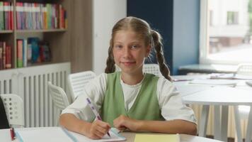 Happy schoolgirl portrait Caucasian kid teen girl child daughter studying in school class primary education pupil learner student learning task write homework academy learn looking at camera smiling video
