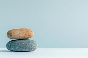 Stones stacked on a minimalist surface with a soft blue background photo