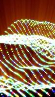 Waves of colorful glowing particles on a bright orange background, creating a dynamic and radiant digital landscape video