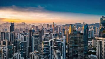 Aerial view of a modern city skyline during sunset with slowly drifting clouds and soft changing light. Glass skyscrapers reflect the warm colors of the sky, creating a calm urban scene. video
