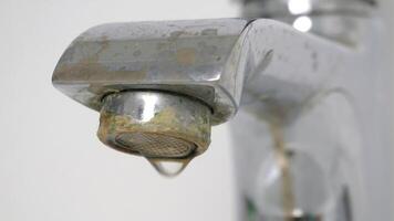 Water is dripping from a damaged faucet. The old faucet was covered with lime scale due to poor water quality and hard water. Useless use of water. Plumbing problems. 4k video