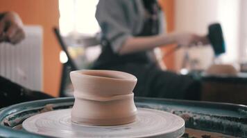 Master is cutting clay cup from potter's wheel, close-up in workshop. She is using wire, and moving ware by hand video