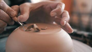 Potter, Craftsman is Working on Pottery Wheel, Rotating the Wheel Fast, Removes Extra Clay, Moulding a Clay Pot, Making a Vessel. Womens's Hands Close Up, dirty hands, pottery workshop, shelves video