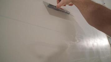 Man plastering the walls with finishing putty in room with putty spatula 11 video