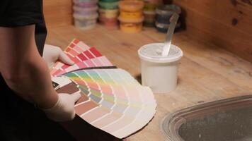 A worker applies a paint sample to a palette for color verification video