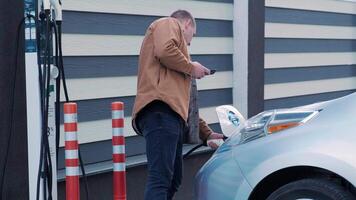Refueling process of an electric car. A shot under the hatch where the electric eco car charges. The electric car charging hatch opens automatically. A male hand inserts an erectile car 46 video
