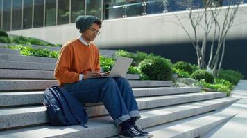 Student browsing on laptop while sitting on steps video