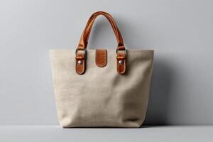 Stylish beige tote bag with leather handles displayed against a simple gray background photo