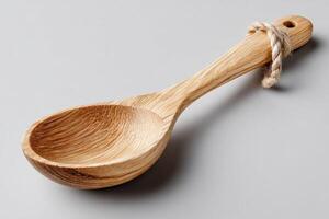 Wooden spoon resting on a neutral surface with natural grain and a twine loop for hanging photo