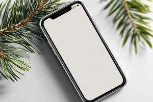 Christmas smartphone resting on a decorative pine branch background with a blank screen ready for holiday photos