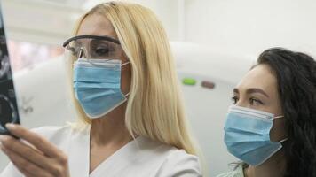 Woman doctor radiologist explains the results of CT scanning for young female patient, showing the snapshot with images, observing and analyzing CT scan in modern clinic beside modern CT scanner 9 video