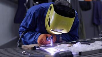 hombre vistiendo máscara soldadura en un taller. metal trabajadores utilizar manual mano de obra. experto soldador. soldador es soldadura el inoxidable acero tubería en el fábrica. soldador industrial parte en fábrica. 13 video