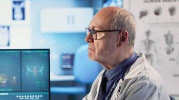 Old man physician and patient meeting at checkup to review x ray scans and lab test results, offers potential treatment for wellness. Healthcare and recovery on medical insurance services. Camera B. video