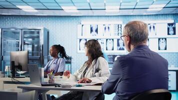 Senior man patient meeting with his doctor to discuss results in an office, using advanced tools to provide diagnostic report. Medic doing x ray scans interpretation, professional approach. Camera A. video