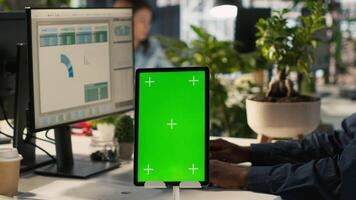 Close up of green screen tablet in front of employee checking progress done on project. Chroma key device next to office clerks reading data statistics on PC screen, camera A video