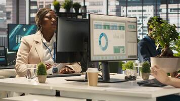 Accountant in busy modern startup agency imputing financial figures on PC after checking reports. Focused businesswoman working in modern office, crosschecking data, camera A video