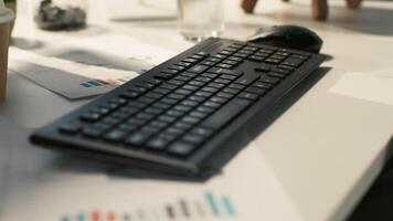Modern workspace with analytical data paperwork documents in bright office environment with potted plants. Tablet on desk with digital statistics charts displayed on screen, close up shot video