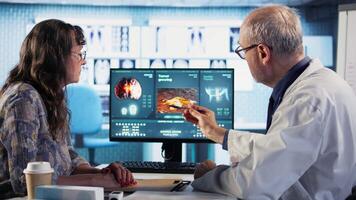 Radiologist discusses an x ray and MRI scan helping a male patient understand preventative measures, immune system protection and treatment options for cancer prevention. Geriatrics. Camera A. video