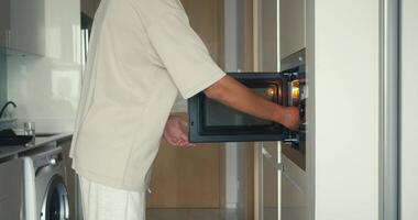 Man using microwave for lunch, microwave boosting convenience in modern kitchen, microwave ensuring quick meal, ideal content for everyday cooking and lifestyle projects worldwide. video