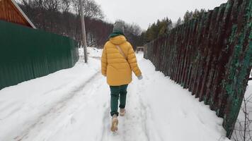 A person walking down a snowy path in a yellow coat video