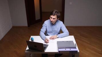 Office worker writing on paper at desk with laptop and folders video