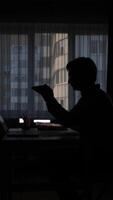 vertical silhouette of a man in the office at his desk crumpling a document video