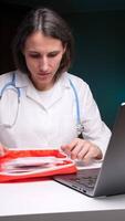 vertical Doctor taking medication from first aid kit while using laptop video