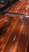 Top view of glowing night traffic weaving through highway interchanges surrounded by futuristic skyscrapers in the smart city of Dubai. Vibrant city lights, modern skyline, and urban architecture video